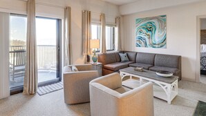 A spacious living room with a sofa set, a coffee table, and a view of the outdoors through large windows. - 2 Mi to Ski Resort! Sugar Mtn Condo w/ Indoor Pool (Sugar Mountain)