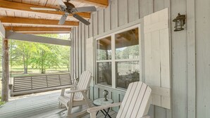 A wooden deck with Adirondack chairs, a ceiling fan, and a view of a grassy area. - Charming Lawley Cottage: Deck, Fire Pit & Yard! (Lawley)