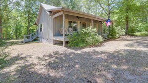 A rustic cabin with a porch, surrounded by trees. - Charming Lawley Cottage: Deck, Fire Pit & Yard! (Lawley)