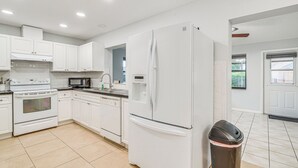 A modern kitchen with white cabinetry, a stove, microwave, and refrigerator.