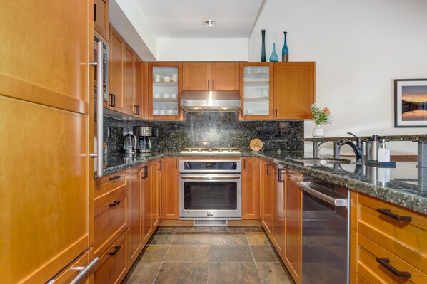 A modern kitchen with wooden cabinets, stainless steel appliances, and a granite countertop. - Montebello 4864 - Private Hot Tub, Air Conditioning, Short Walk to the Village (Whistler)