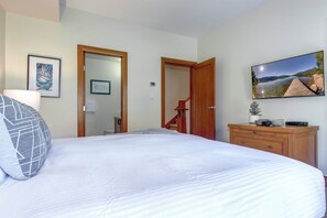A bedroom with a large bed, a wooden dresser, a television, and a framed picture on the wall. - Montebello 4864 - Private Hot Tub, Air Conditioning, Short Walk to the Village (Whistler)
