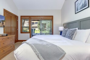 A bedroom with a large bed, a wooden dresser, a sliding glass door leading to a balcony, and a framed picture on the wall. - Montebello 4864 - Private Hot Tub, Air Conditioning, Short Walk to the Village (Whistler)