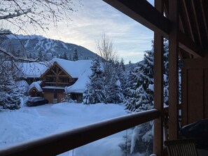 A wooden cabin with a snow-covered roof and a view of snow-covered trees and mountains. - Montebello 4864 - Private Hot Tub, Air Conditioning, Short Walk to the Village (Whistler)