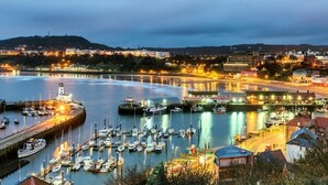 Un puerto con barcos amarrados, un faro y edificios a lo largo del muelle.