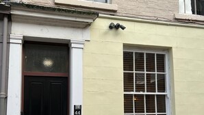 Un edificio de dos pisos con una puerta negra y un ventanal de diseño cuadriculado.