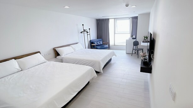 A hotel room with two beds, a desk, a chair, and a television. - 3rd Alley Inn (Kaohsiung)