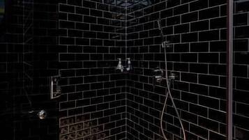A shower with black tiles and a geometric patterned floor.
