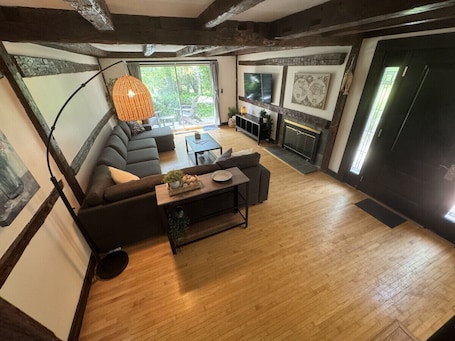 A spacious living area with a wooden floor, a sofa set, a coffee table, and a fireplace.