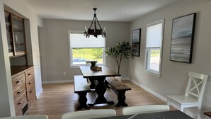 A dining area with a marble table, wooden benches, and a chandelier. - The Blue Anchor House · walk Mystic-Train/Aquarium (Stonington)