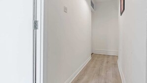 A narrow hallway with white walls and a wooden floor. - Cedar View – 2 Bed Apartment (Newport)
