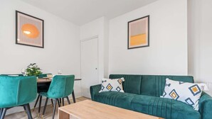 Un salon moderne avec un canapé vert, une table basse en bois et un coin repas avec des chaises vertes.