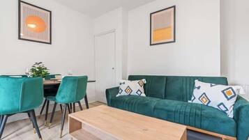 Una sala de estar moderna con un sofá verde, una mesa de centro de madera y un comedor con sillas verdes.