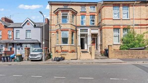 A row of terraced houses with a central entrance and a car parked on the street. - Cedar View – 2 Bed Apartment (Newport)