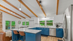 Une cuisine moderne avec des armoires bleues, un grand îlot central et un réfrigérateur en acier inoxydable.