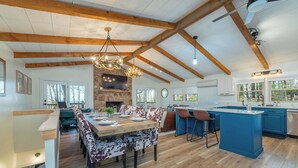 Une cuisine spacieuse dotée d’un grand îlot central, de poutres en bois et d’une cheminée en pierre.