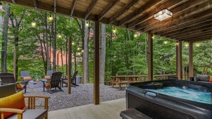 Un espace extérieur aménagé avec des chaises et un jacuzzi, le tout installé sous une pergola en bois illuminée de guirlandes lumineuses.