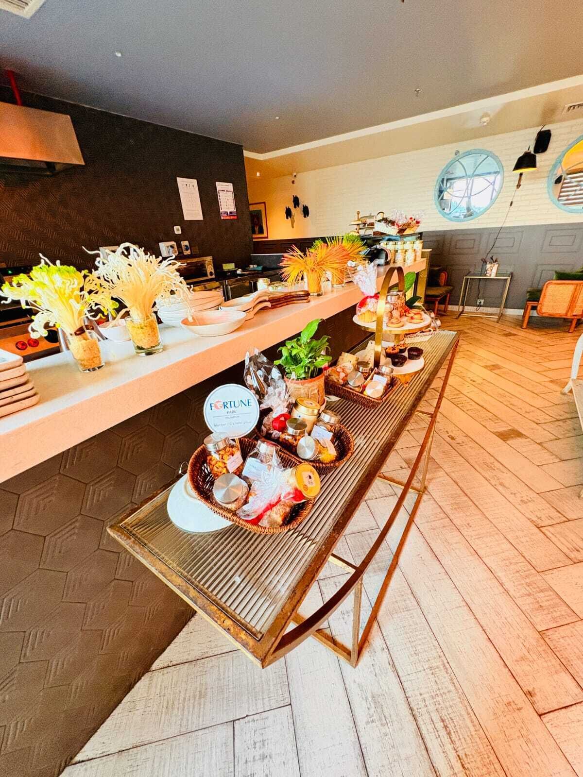 Disposição de buffet com diversos alimentos e plantas decorativas.