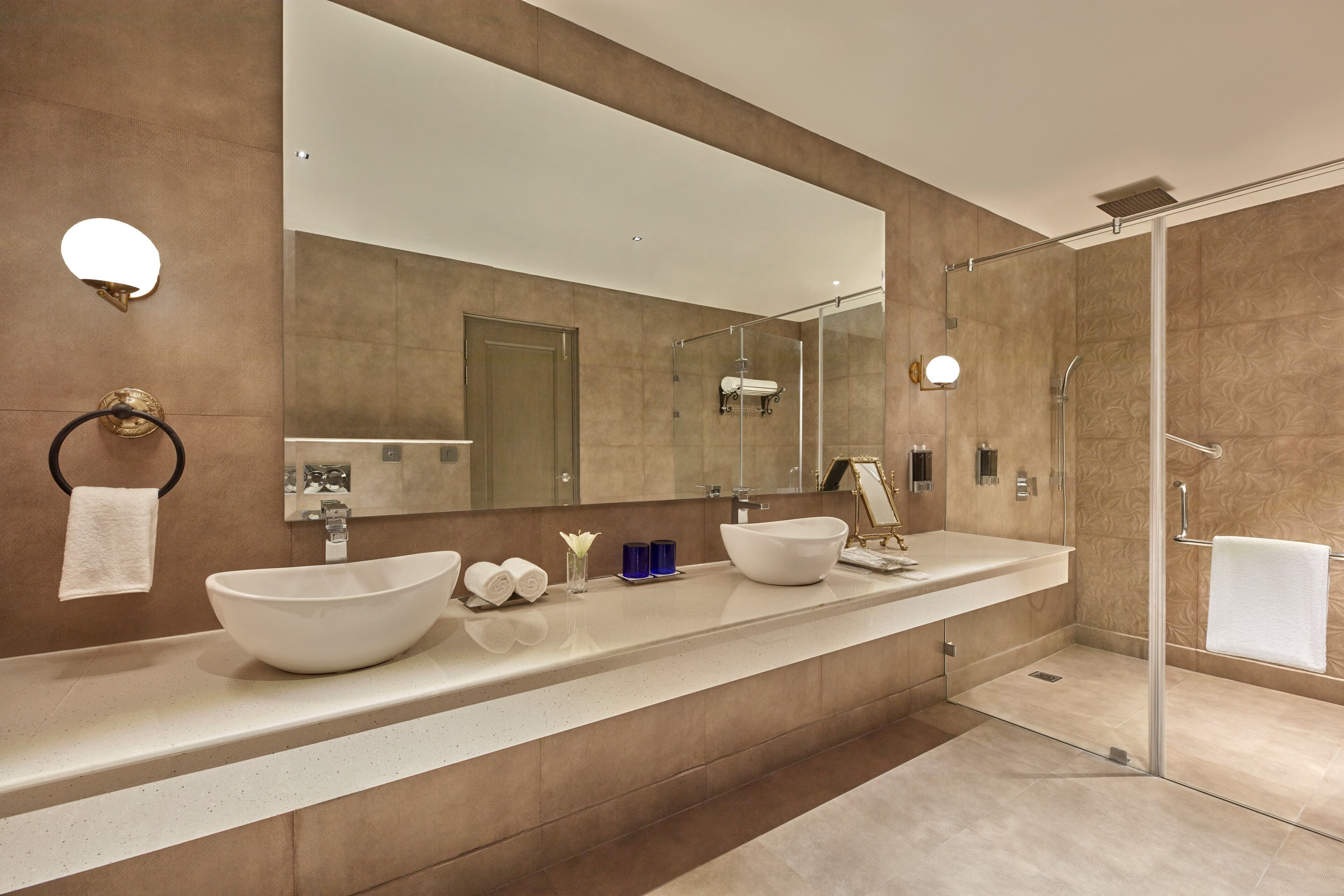 A modern bathroom with two large sinks, a large mirror, and a glass-enclosed shower.