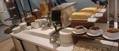 A buffet setup with various food items, plates, and serving utensils.