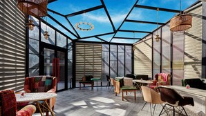 A spacious room with a high ceiling, large windows, and a variety of seating options including chairs and sofas. - Fortune Park Palampur - Member ITC Hotels' Group (Palampur)
