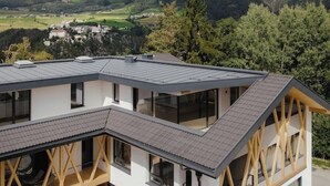Ein modernes Gebäude mit einem geneigten Dach, großen Fenstern und Blick auf ein Tal.