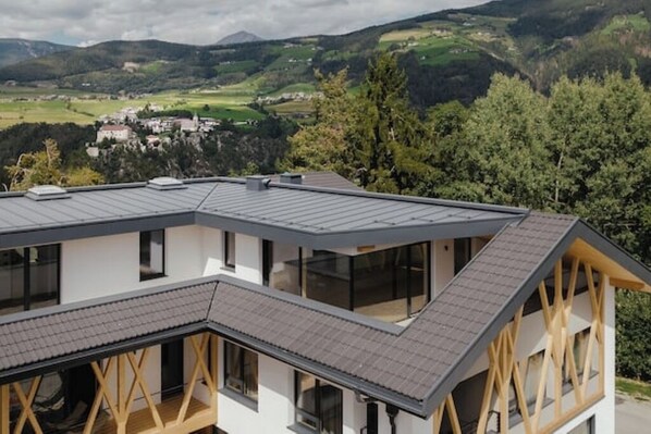 A modern building with a sloped roof, large windows, and a view of a valley. - Farm apartment with panoramic view of Rodenegg Castle (Naz-Sciaves)