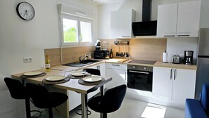 A modern kitchen with a dining area, equipped with a stove, oven, and various appliances.