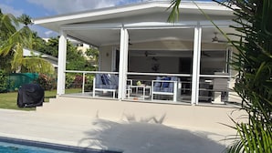 Un'area esterna coperta con piscina, sedie a sdraio e ventilatore a soffitto.