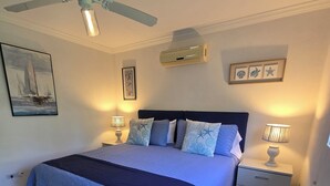 Una camera da letto con un letto, due comodini, una ventola a soffitto e condizionatore d'aria a parete.
