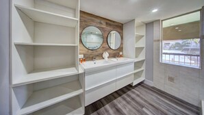 Een moderne badkamer met twee wasbakken, houten wandbekleding en ingebouwde planken.