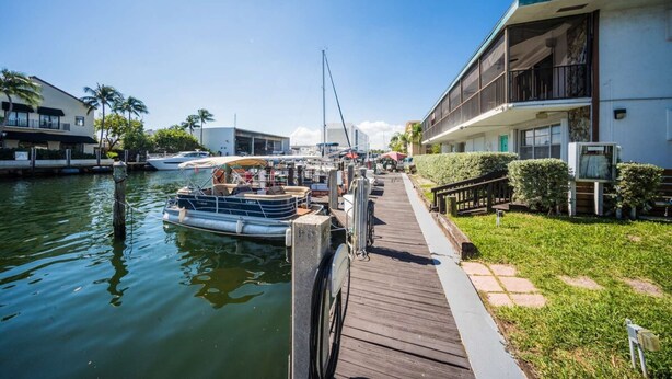 A marina with boats docked, a wooden walkway, and a building with balconies. - Mahalo Waterfront 1 BR Apartment (Fort Lauderdale)