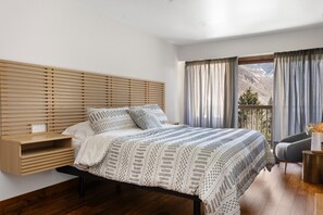 A bedroom with a bed, bedside table, and a view of the outdoors. - Fallridge Condo - Near Golf Course & Bus (Vail)