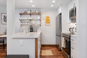 A modern kitchen with white cabinetry, a built-in oven, and a coffee machine. - Fallridge Condo - Near Golf Course & Bus (Vail)
