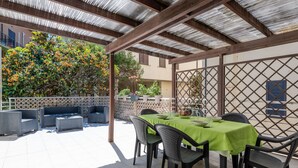 An outdoor patio with a covered seating area, a table set for dining, and potted plants. - Vacation home Elena by Interhome (Castiglione della Pescaia)