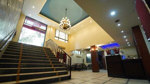A hotel lobby with a staircase, a reception desk, and a chandelier. - Hotel Saket (Prayagraj)