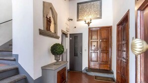 A hallway with a staircase, a door, and a wall-mounted plaque. - Florence Rooftop Apt - Jacuzzi & Panoramic View (Firenze)