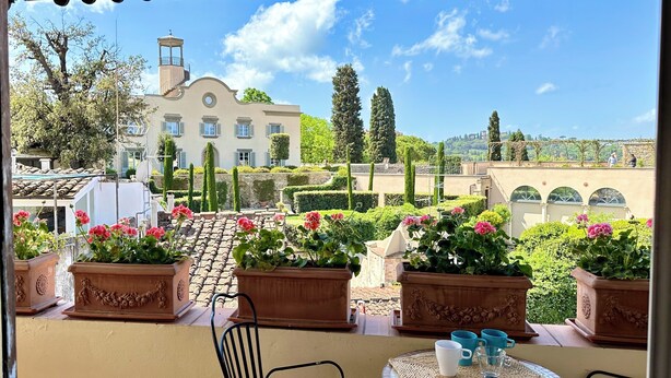 A terrace with a view of a large building, potted plants, and a table with chairs. - Florence Rooftop Apt - Jacuzzi & Panoramic View (Firenze)