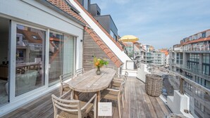 A wooden deck with a table and chairs, a wicker basket, and a sign indicating 'Floor 1 Seaside'.