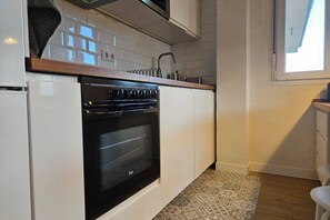 Een keuken met witte kastjes, een zwarte oven en een tapijt met een patroon.