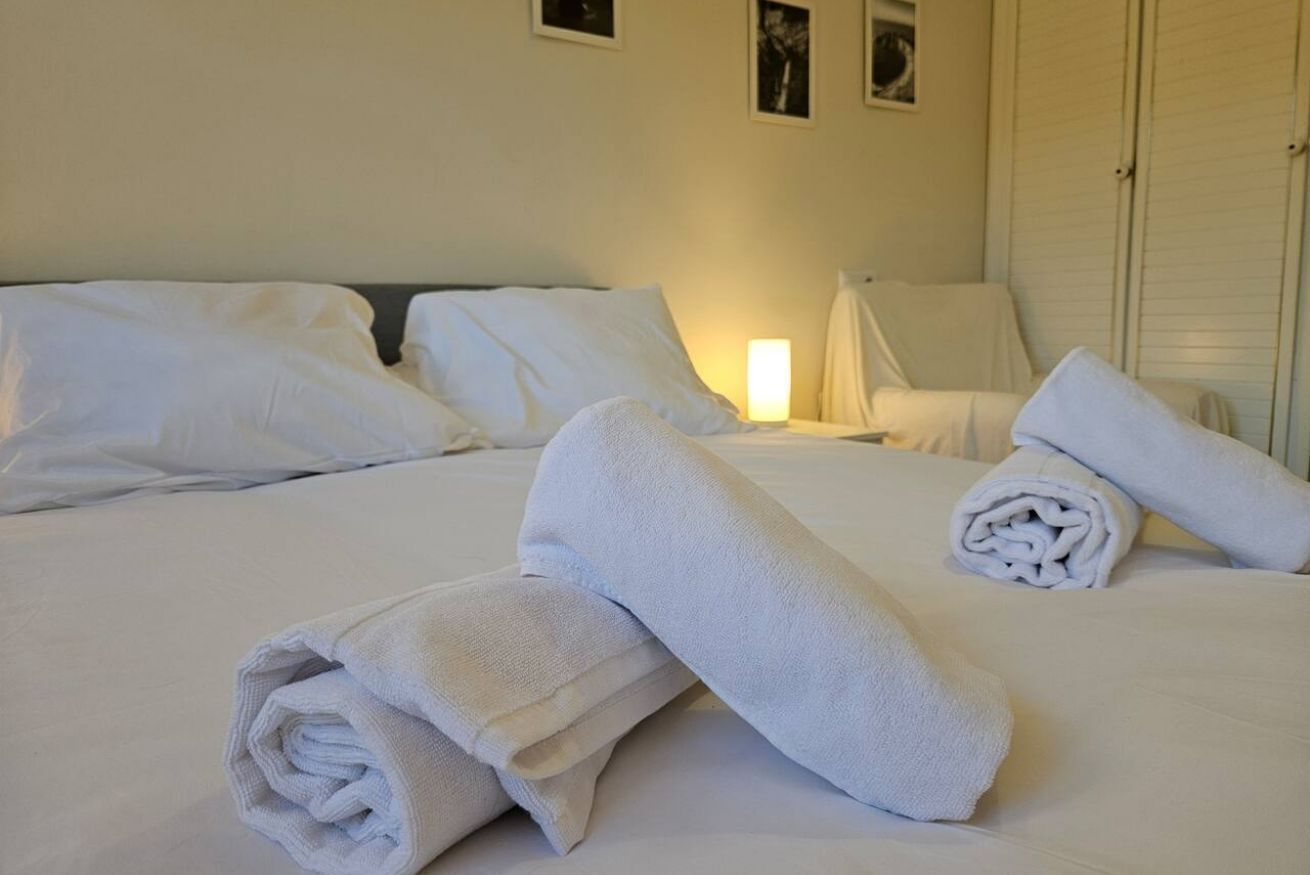 A hotel room with a neatly made bed, a chair, and a lamp.