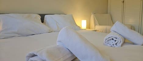 A hotel room with a neatly made bed, a chair, and a lamp.