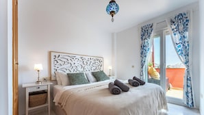 A bedroom with a bed, nightstands, a decorative headboard, and a view of the outside. - Amazing Sea and Golf Course view 2BR, Parking Pool REF037 (Benalmádena)