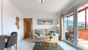 A modern living room with a sofa, a coffee table, and a dining area. - Amazing Sea and Golf Course view 2BR, Parking Pool REF037 (Benalmádena)