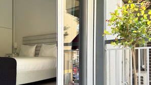 Un dormitorio con cama, mesita de noche, lámpara y vistas al exterior a través de un ventanal.