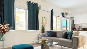 Una sala de estar moderna con sofá, reposapiés y una mesa de centro de vidrio.