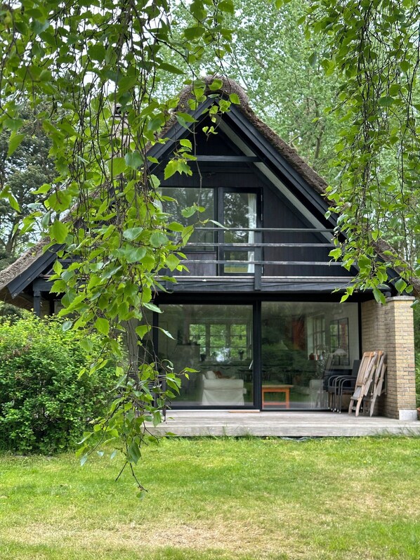A modern house with a large glass window, a balcony, and a brick exterior.