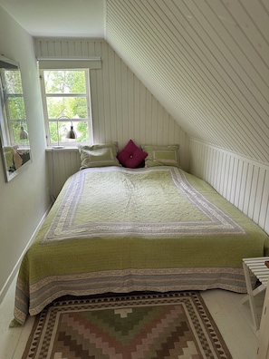 A bedroom with a bed, a window, a radiator, and a patterned rug.