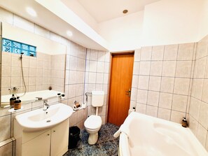 Bathroom features a sink, toilet, and bathtub, with a tiled floor and walls.