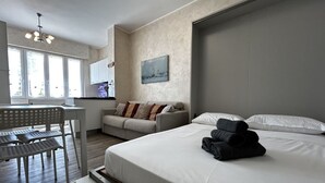 A modern hotel room with a bed, a sofa, a dining area, and a painting on the wall. - [50m from the Beach] Modern Studio with WiFi & A/C (Lido Di fermo)